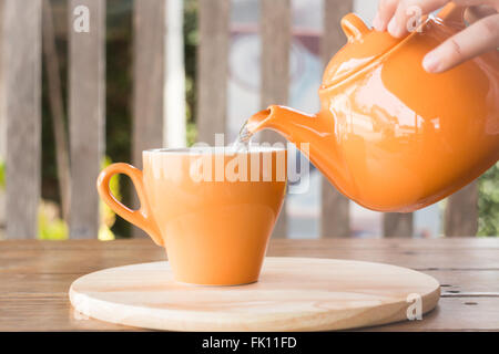 Heißer Tee wird in einer Tasse, Foto von Teekanne gegossen. Stockfoto