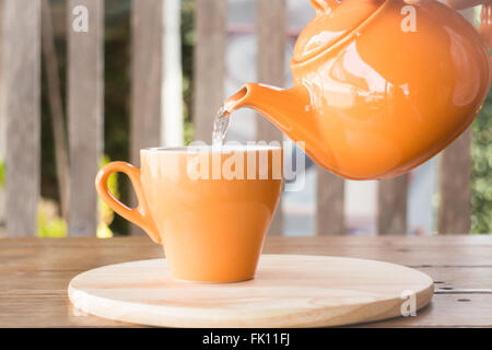 Heißer Tee wird in einer Tasse, Foto von Teekanne gegossen. Stockfoto