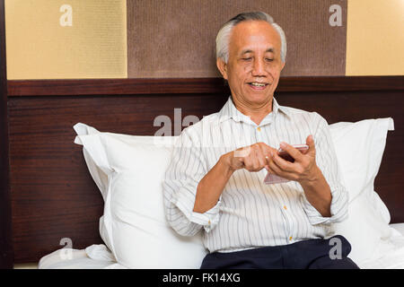 Glücklich asiatischen Geschäftsmann mit Telefon im Hotel genießen. Stockfoto