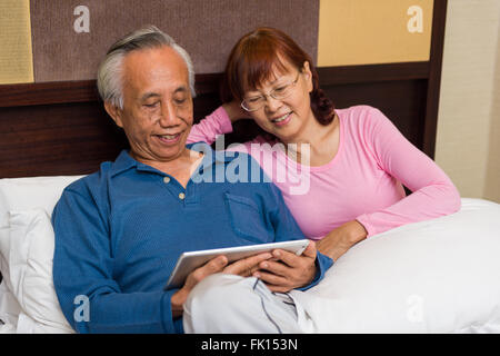 Asiatische älteres Paar teilen und genießen mobile Unterhaltung. Stockfoto