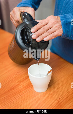 Gießen heißes Wasser aus der Flasche in Tasse. Stockfoto