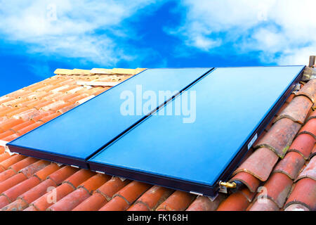 Sonnenkollektoren auf dem Dach eines Hauses mit blauem Himmelshintergrund installiert Stockfoto