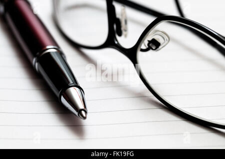 Bild von eine Nahaufnahme von einem roten und schwarzen Stift und Rezept Gläser auf Liniertes Notizbuch Papier. Stockfoto