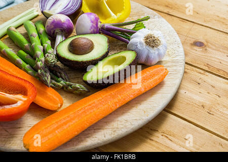 Mischung aus frischem Gemüse in Scheiben geschnitten auf einem Holztisch, Rundweg, Spargel, Avocado, Paprika, Zwiebel Stockfoto
