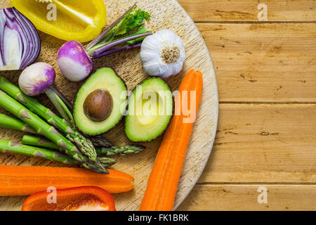 Frisches Gemüse in Scheiben geschnitten in Hälfte auf einem Holztisch, Rundweg, Spargel, Avocado, Paprika, Zwiebel, Platz für text Stockfoto