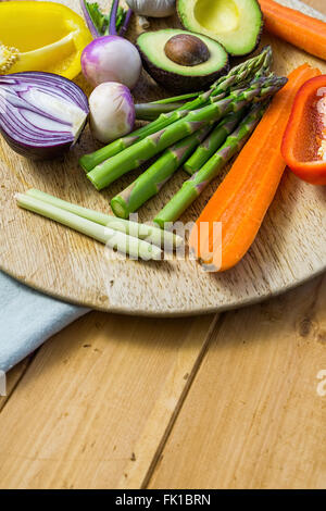 Frisches Gemüse in Scheiben geschnitten auf einem Holztisch, Rundweg, Spargel, Avocado, Paprika, Zwiebel Stockfoto