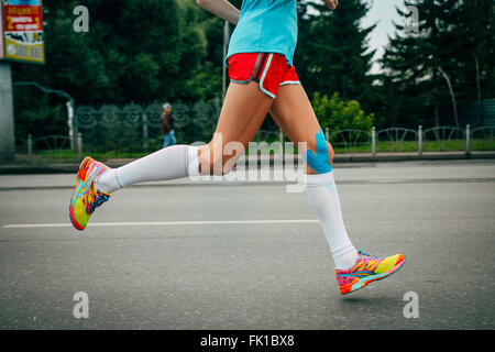 Mädchen-Athlet Marathonlauf, Knien im blauen Bereich Kinesiologisches taping Stockfoto