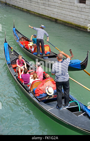 Venedig Gondel Familie Gruppe von Touristen auf Besichtigungstour Fahrt entlang des engen Kanals mit Gondoliere zeigt auf Sehenswürdigkeiten von Interesse zwei von einer Art Italien Stockfoto