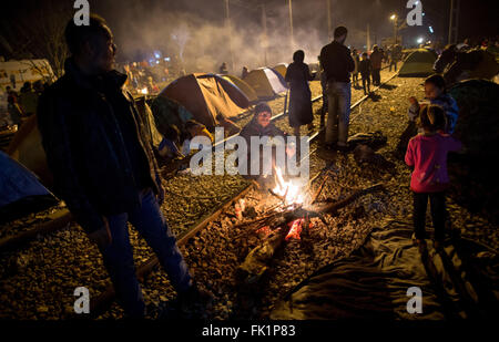 Idomeni, Griechenland. 5. März 2015. Flüchtlinge sitzen auf Bahnschienen durch ein Lagerfeuer vor ihren Zelten im Flüchtlingslager an der griechisch-mazedonischen Grenze in Idomeni, Griechenland, 5. März 2015. Nur wenige Flüchtlinge aus Syrien und dem Irak werden über die Grenze nach Mazedonien jeden Tag vermietet werden. Foto: KAY NIETFELD/Dpa/Alamy Live News Stockfoto