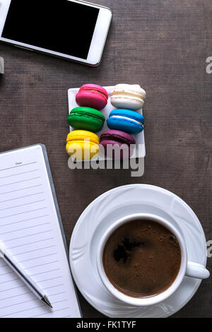 Tasse Kaffee und bunte Makronen auf dem Schreibtisch Stockfoto