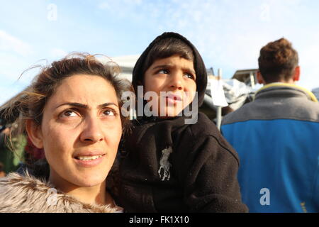 Idomeni, Griechenland, 5. März 2016.  Eine Frau trägt ein Kind in einem Flüchtlingslager an der Grenze des griechisch-Makedonien.  Das Durchgangslager an der griechischen mazedonischen Grenze ist immer überfüllt immer, wie Tausende von Flüchtlingen weiterhin ankommen und dort warten, bis die Grenze nach Mazedonien. Rund 11.000 Flüchtlinge bleiben nun an der Grenze, in der Nähe der griechischen Dorf Idomeni stecken, während sie darauf warten, in Mazedonien weiterhin ihre Reise nach Westeuropa eingeben. Mazedonien ist für Flüchtlinge nur beschränktem Zugang ermöglicht. Bildnachweis: Orhan Zolak / Alamy Live News Stockfoto