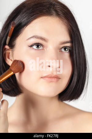 Das Mädchen tut Make-up auf weißem Hintergrund Stockfoto