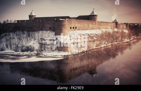 Ivangorod Festung am Fluss Narva in der Wintersaison. Grenze zwischen Russland und Estland. Vintage stilisierte Foto Stockfoto