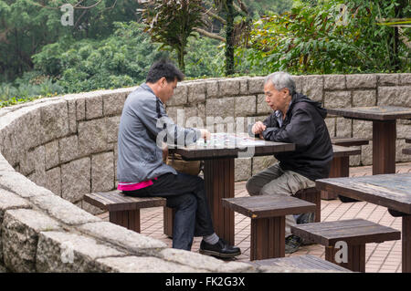 Zwei chinesische Männer spielen ein Brettspiel in Kowloon Park, Tsim Sha Tsui, Kowloon, Hong Kong, China. Stockfoto