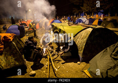 Idomeni, Griechenland. 5. März 2016. Junge Männer sitzen um ein Lagerfeuer draußen ihre Zelte im Flüchtlingslager nahe der griechisch-mazedonischen Grenze in der Nähe von Idomeni, Griechenland, 5. März 2016. Nur wenige Flüchtlinge aus Syrien und dem Irak werden über die Grenze nach Mazedonien jeden Tag vermietet werden. Foto: KAY NIETFELD/Dpa/Alamy Live News Stockfoto