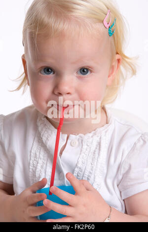 Kleinkind Mädchen ist trinken Limonade mit A Stroh auf weißem Hintergrund Stockfoto