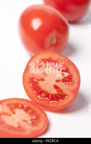 Ganze und halbe frische rote Tomaten auf weißem Hintergrund Stockfoto