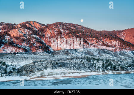 Mond-Einstellung über Arhturs Rock beleuchtet mit Horsetooth Reservoir von Eis, Fort Collins, Colorado bedeckt von Sunrise. Stockfoto