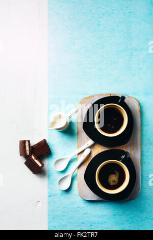 Morgen-Kaffee-Tisch. Zwei Tassen Espresso mit Milch und Schokolade Kuchen Kanne. Tiefenschärfe, Ansicht von oben. Stockfoto