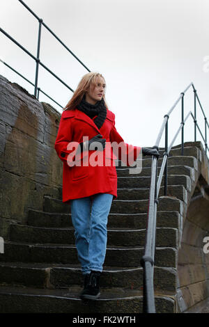 Junge Frau zu Fuß einige alte Treppe hinunter auf einen nassen Wintertag Stockfoto