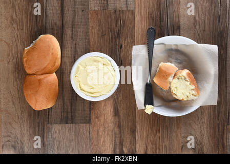 Draufsicht des Abendessens rollt Brotteller und Butter Crock auf einem rustikalen Holztisch. Stockfoto