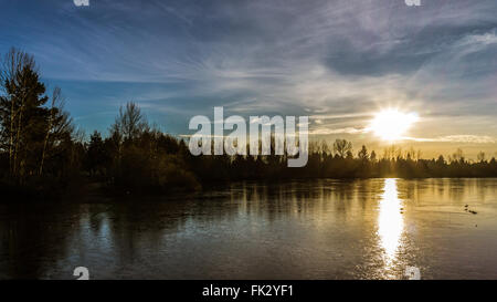 Sonnenuntergang über eine teilweise gefrorenen Mühlensee in der Wintersaison von Abbotsford, British Columbia Stockfoto