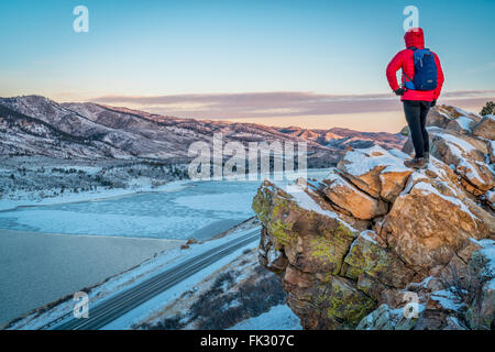 männliche Wanderer Betrachtung Winter Sonnenaufgang über gefrorene Horsetooth Reservoir an Ausläufern der Rocky Mountains Stockfoto