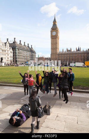 Eine Gruppe chinesischer Touristen in London, die vor Big Ben in die Luft springen, Parliament Square London UK. Chinesische Touristen in Großbritannien. Stockfoto