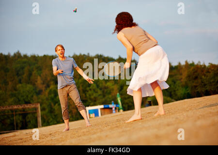 Glückliches Paar zusammen zu spielen Badminton am Strand im Sommer Stockfoto