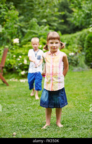 Zwei Kinder spielen zusammen in einem Garten und ziehen eine Zeichenfolge Stockfoto