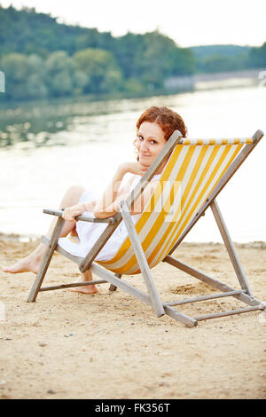 Frau Verlegung entspannt im Liegestuhl im Sommer am Strand Stockfoto