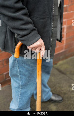 Älterer Mann hält einen Spazierstock Stockfoto