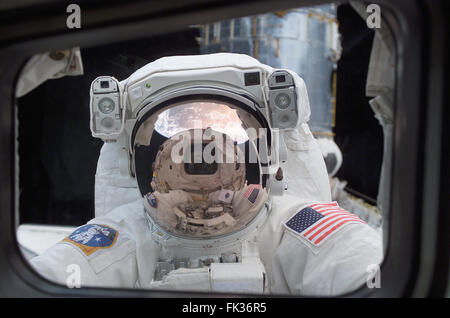 NASA-Astronaut John Grunsfeld schaut in die Crew-Kabine des Space Shuttle Columbia aus dem Weltraum während der ersten STS-109 Extravehicular Tätigkeit 4. März 2002 in der Erdumlaufbahn. Grunsfeld das Helmvisier mit Sonnenschutz jetzt in platzieren, zeigt gespiegelte Bilder von der Erde und das Space Shuttle Columbia Achterkabine. Stockfoto