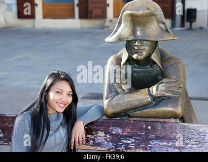 Asiatische Touristen Frau sitzen auf Bank mit Napoleon Soldaten am Hauptplatz, Bratislava, Slowakei Stockfoto