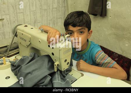 Ein Junge kurdische Schneider in der Werkstatt seines Vaters in Erbil Basar. Stockfoto