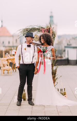 Bezaubernde afrikanische Brautpaar verträumt blickt auf einander. Tag der Hochzeit. Auf dem Dach. Lemberg Architektur auf Hintergrund Stockfoto