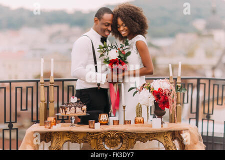 Romantische afrikanische Hochzeitspaar auf der Terrasse. Luxuriöse golden Tabelle im orientalischen Stil im Vordergrund Stockfoto