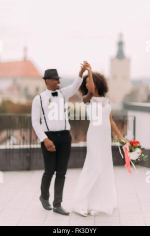 Schwarz, frisch vermählte Brautpaar tanzt anmutig auf dem Dach. Hochzeitstag Stockfoto