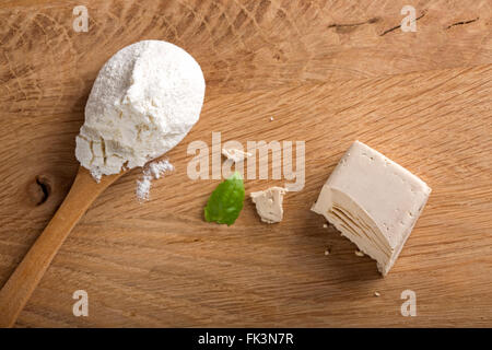 Zerbröckelte Hefe Würfel auf einem Holzbrett und einem Löffel Weißmehl Stockfoto