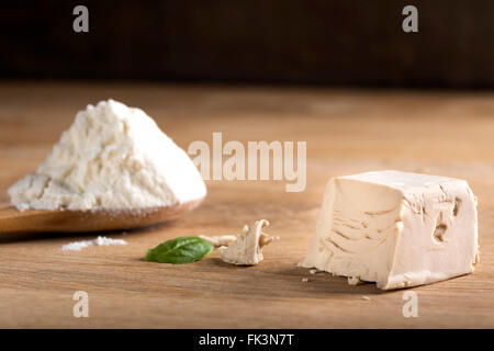 Zerbröckelte Hefe Würfel auf einem Holzbrett und einem Löffel Weißmehl Stockfoto