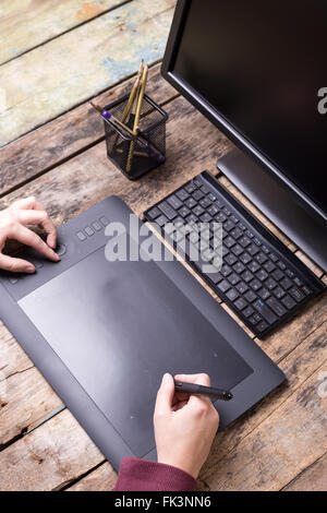 Arbeitsplatz des Grafikdesigners auf Holztisch. Künstler Zeichnung auf Grafiktablett an der Rezeption. Draufsicht Bild Stockfoto