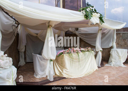 Tisch für ein Hochzeitsessen, dekoriert mit Blumen und einer Seidenschleife Stockfoto