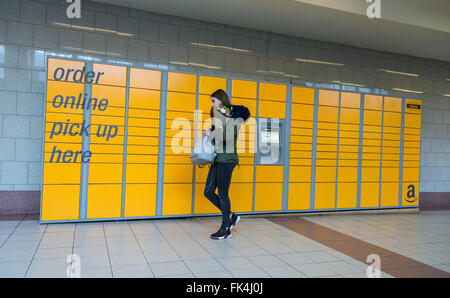 Eine junge Frau holt Blumen von einem Amazon-Selbstbedienungskiosks im Hammersmith Broadway Shopping Centre, London, England, Großbritannien. Stockfoto