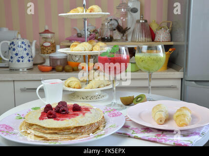 Weiche Pfannkuchen mit natürlichen Himbeer-Gelee, frische Croissants und Himbeere und Kiwi Smoothies zum Frühstück serviert Stockfoto