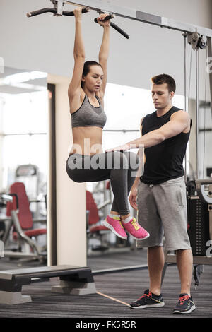 junge Frau mit Trainer tun Bein hebt im Fitness-Studio Stockfoto