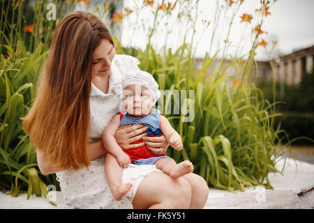 Niedliche glücklich Kleinkind auf liebevolle Mutter Knien sitzen und Lächeln auf den Lippen. Familienspaß. Selektiven Fokus. Stockfoto