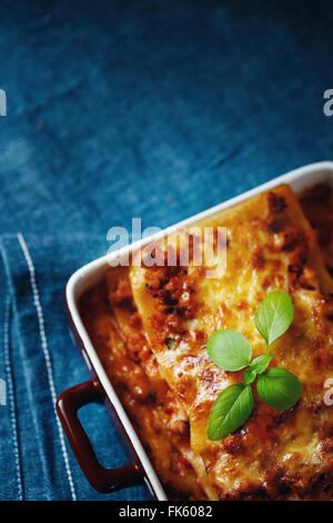 Italienisches Essen. Draufsicht der heißen frisch gebackene Lasagne-Platte auf blau Textil-Hintergrund. Nahaufnahme, selektiven Fokus. Raum für Ihre Stockfoto
