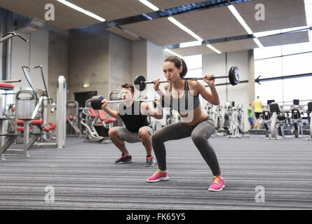 junger Mann und Frau mit Langhantel im Fitness-Studio trainieren Stockfoto
