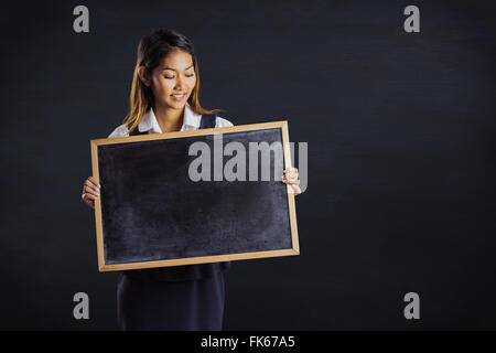 Zusammengesetztes Bild des lächelnden Geschäftsfrau hält eine Tafel Stockfoto