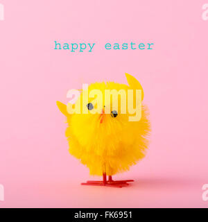 eine bunte gelb Teddy-Küken und dem Text Frohe Ostern vor einem rosa Hintergrund Stockfoto